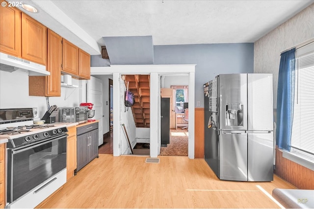 8014 N Johnswood Dr, Portland, OR 97203 - kitchen with gas stove, stainless steel fridge, under cabinet range hood, light wood-style flooring, and light countertops