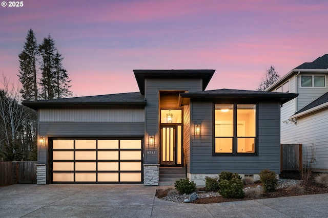 modern home with a garage, driveway, and fence