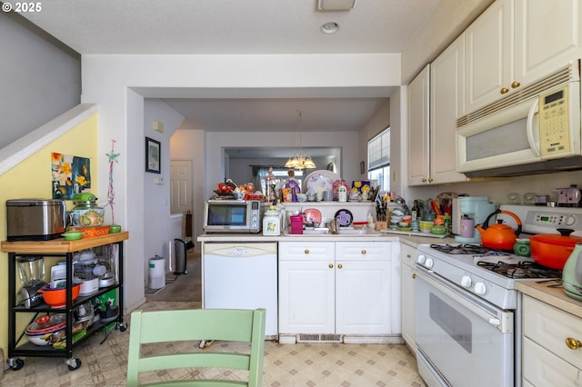 kitchen with pendant lighting, a notable chandelier, white appliances, and white cabinets