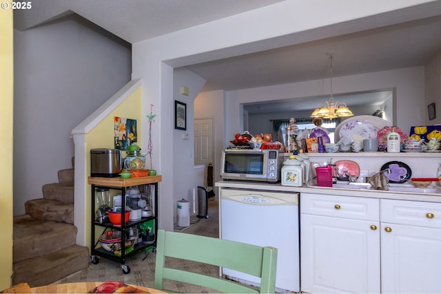 kitchen featuring dishwasher, a notable chandelier, pendant lighting, carpet, and white cabinets