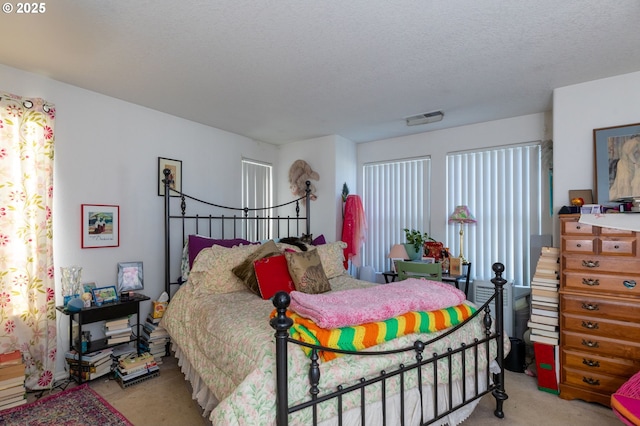 carpeted bedroom featuring multiple windows and a textured ceiling