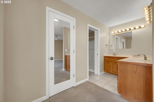 bathroom featuring vanity, a walk in closet, baseboards, and tile patterned flooring