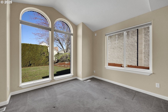 spare room featuring vaulted ceiling, carpet flooring, visible vents, and baseboards