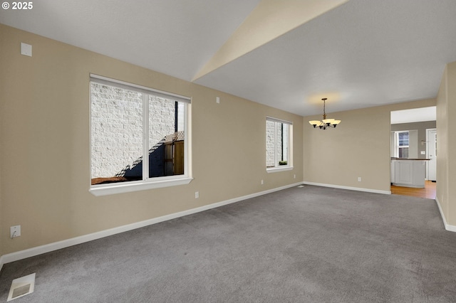 carpeted spare room featuring a wealth of natural light, visible vents, baseboards, and a notable chandelier
