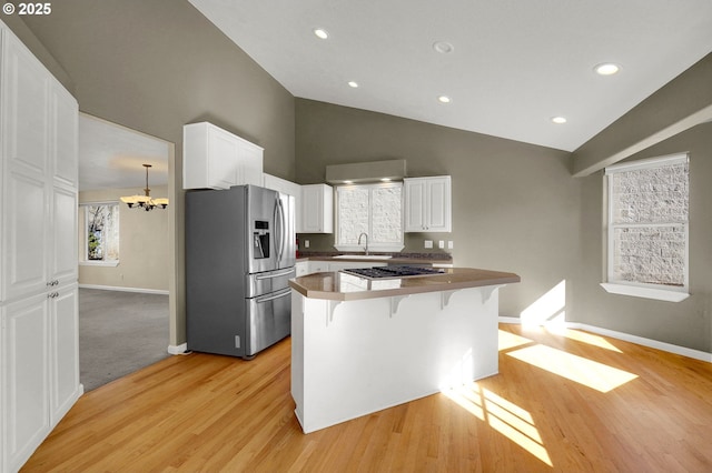 kitchen with a kitchen bar, a sink, appliances with stainless steel finishes, white cabinets, and baseboards