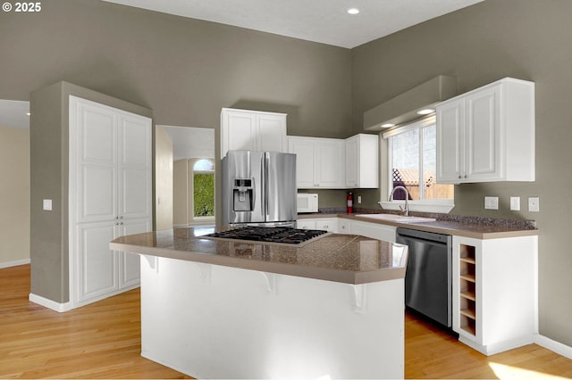 kitchen featuring a sink, white cabinets, light wood-style floors, and stainless steel appliances