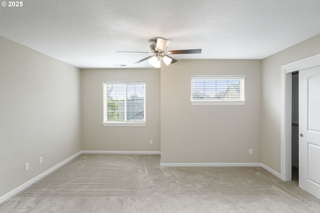 unfurnished room featuring plenty of natural light, a ceiling fan, light carpet, and a textured ceiling
