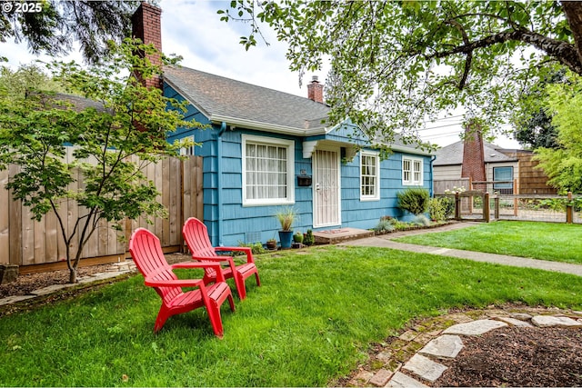 view of front of house with a front lawn, a chimney, fence private yard, and roof with shingles
