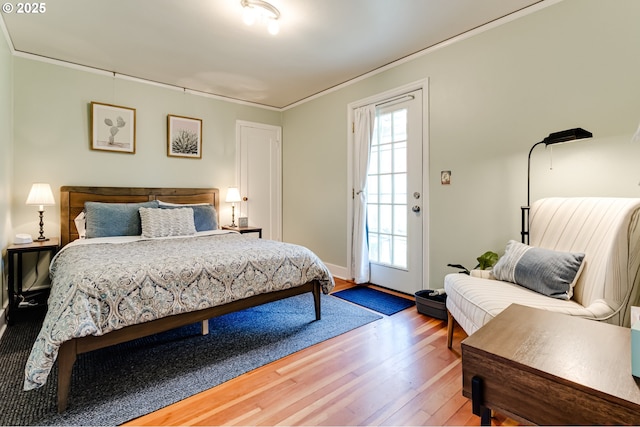 bedroom featuring wood finished floors, access to outside, and ornamental molding