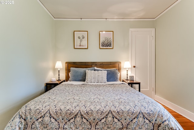bedroom with wood finished floors, crown molding, and baseboards