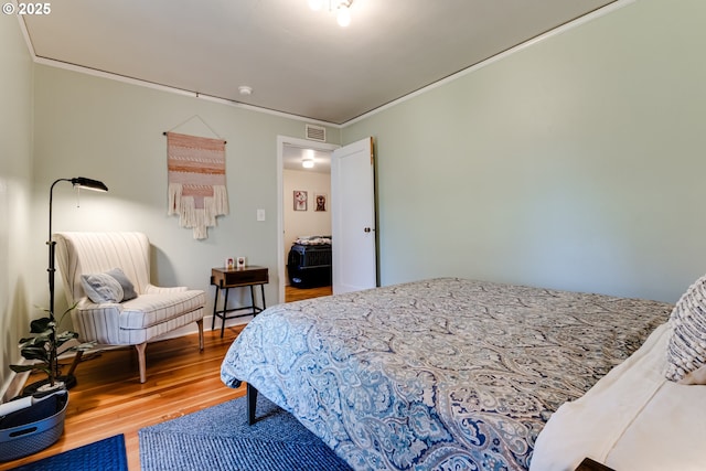 bedroom featuring ornamental molding, wood finished floors, and visible vents