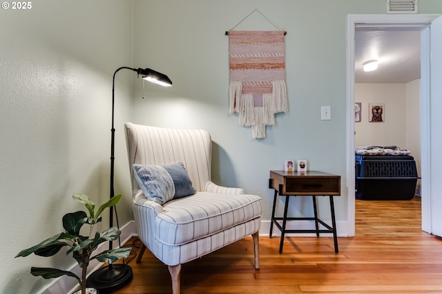 living area featuring baseboards, wood finished floors, and visible vents