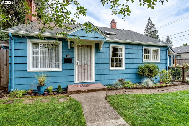 view of front of home featuring a chimney, a front lawn, fence, and roof with shingles