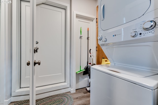 laundry room with stacked washer / drying machine, light wood-style floors, and laundry area