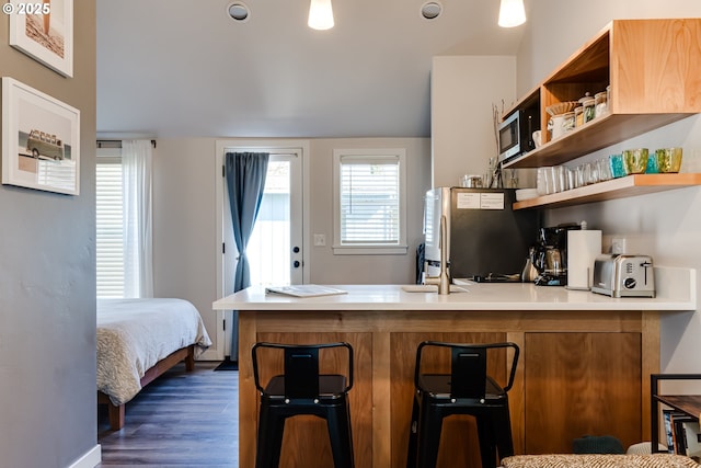 kitchen with open shelves, light countertops, dark wood finished floors, a peninsula, and freestanding refrigerator
