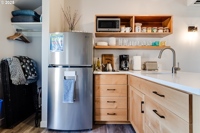 kitchen with light brown cabinets, dark wood-style flooring, stainless steel appliances, and a sink