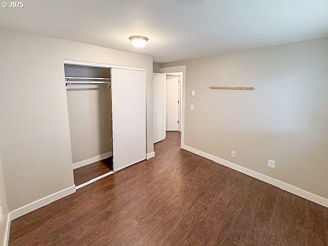 unfurnished bedroom featuring dark wood-type flooring and a closet