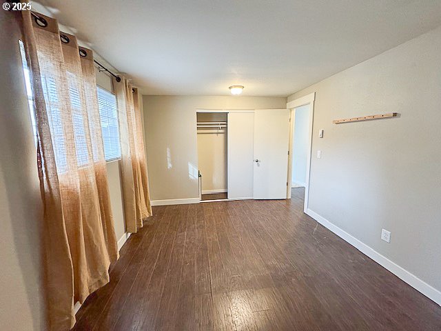 unfurnished bedroom featuring dark hardwood / wood-style flooring and a closet