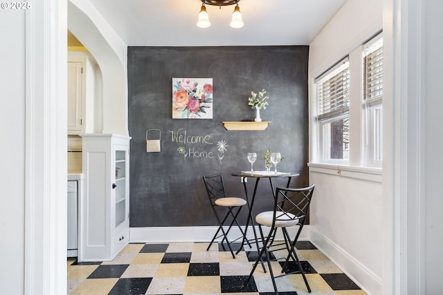 dining space with baseboards, an accent wall, and tile patterned floors