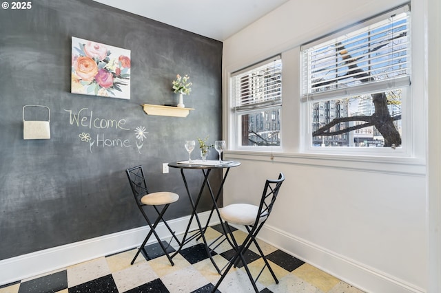 dining area with an accent wall, baseboards, and tile patterned floors