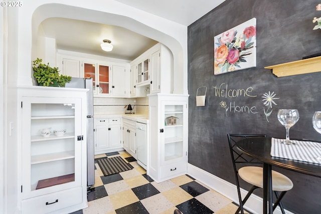 kitchen with white cabinets, glass insert cabinets, white dishwasher, light countertops, and light floors