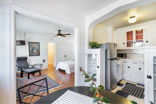 kitchen with appliances with stainless steel finishes, white cabinetry, light wood-style flooring, and tasteful backsplash