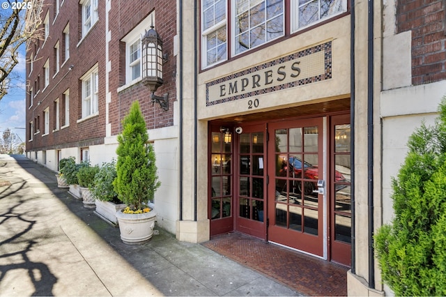 view of exterior entry featuring french doors and brick siding