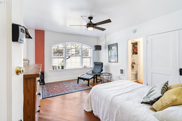 bedroom with ensuite bathroom, ceiling fan, baseboards, and wood finished floors