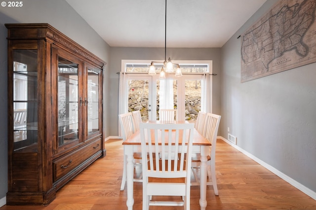 dining area with baseboards, a chandelier, and light wood-style floors