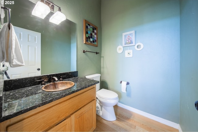 bathroom featuring baseboards, vanity, toilet, and wood finished floors