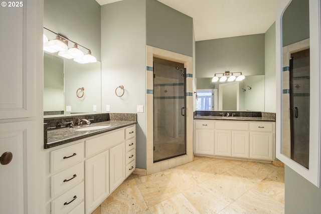 bathroom featuring a shower stall, two vanities, and a sink