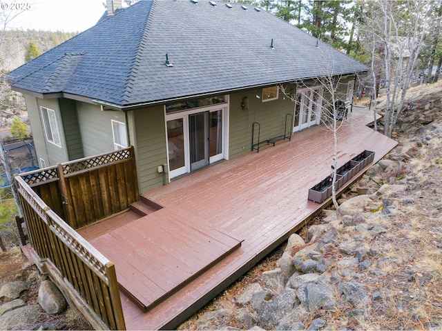 rear view of property featuring a chimney, french doors, roof with shingles, and a deck