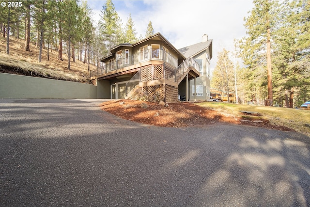 chalet / cabin with a chimney, driveway, and a deck