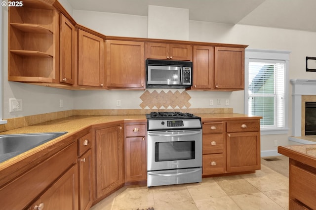 3435 Meadow View Dr, Eugene, OR 97408 - kitchen with appliances with stainless steel finishes, light countertops, brown cabinets, and a glass covered fireplace