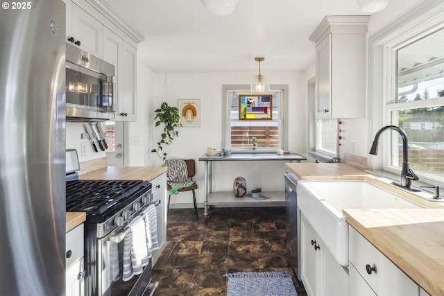 7615 SE 66th Ave, Portland, OR 97206 - kitchen with appliances with stainless steel finishes, wooden counters, white cabinets, a sink, and hanging light fixtures