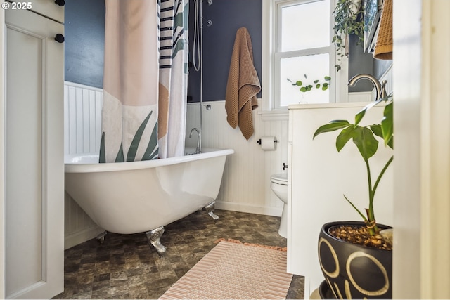 7615 SE 66th Ave, Portland, OR 97206 - bathroom with a wainscoted wall, a soaking tub, toilet, and baseboards