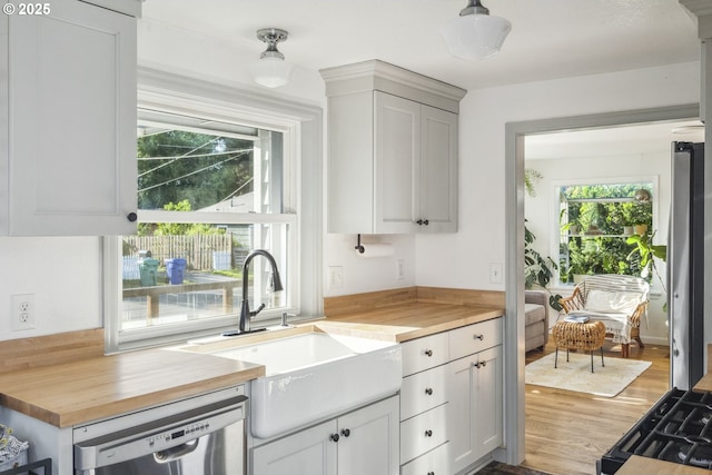 7615 SE 66th Ave, Portland, OR 97206 - kitchen with dishwasher, wooden counters, a sink, wood finished floors, and white cabinetry