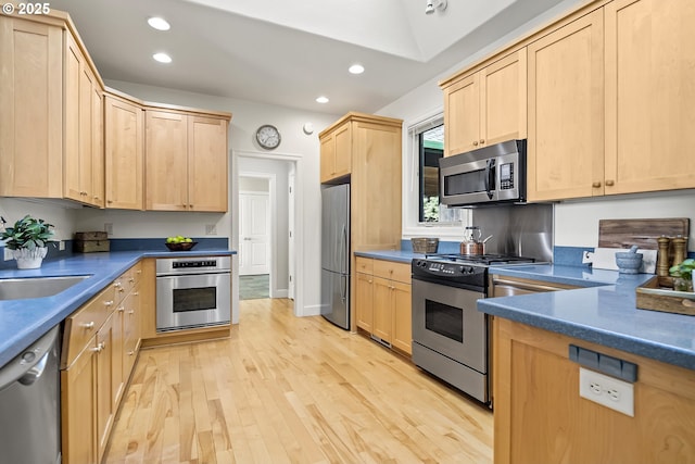 kitchen with light wood-type flooring, light brown cabinets, dark countertops, recessed lighting, and appliances with stainless steel finishes