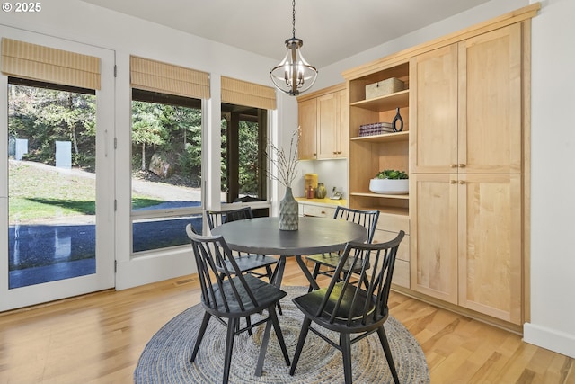 dining space with light wood finished floors and an inviting chandelier