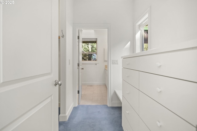 hallway featuring light colored carpet and baseboards