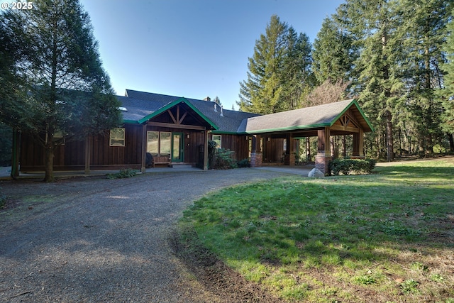 view of front of house with board and batten siding, gravel driveway, and a front yard