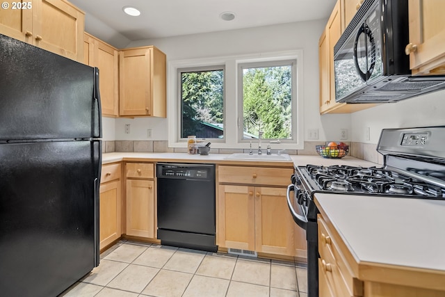 kitchen featuring light tile patterned floors, a sink, light brown cabinetry, black appliances, and light countertops