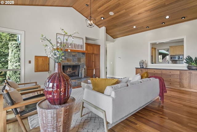 living area featuring a fireplace, vaulted ceiling, wood ceiling, and a wealth of natural light