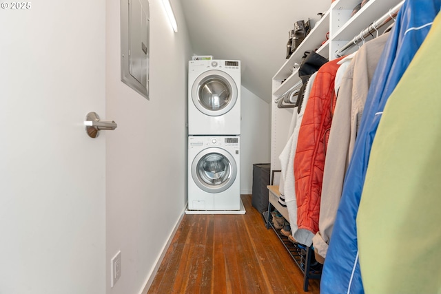 laundry area featuring stacked washer / drying machine, electric panel, wood-type flooring, and baseboards