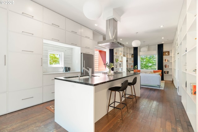 kitchen featuring modern cabinets, high quality fridge, dark wood-type flooring, a sink, and island range hood