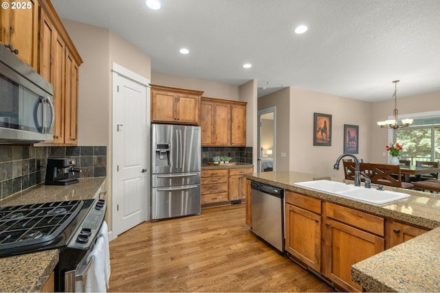 14746 SW 148th Ter, Tigard, OR 97224 - kitchen featuring appliances with stainless steel finishes, brown cabinets, light wood-style flooring, backsplash, and a chandelier