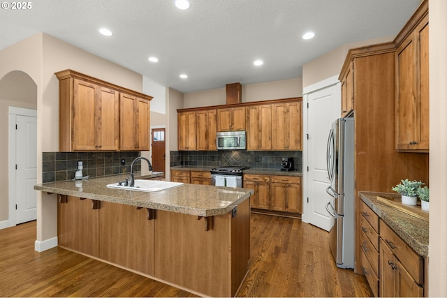14746 SW 148th Ter, Tigard, OR 97224 - kitchen featuring appliances with stainless steel finishes, a peninsula, brown cabinets, backsplash, and recessed lighting
