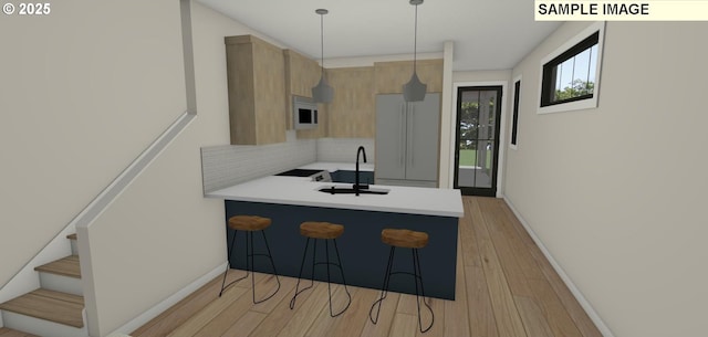 kitchen with light wood-type flooring, tasteful backsplash, white appliances, sink, and hanging light fixtures