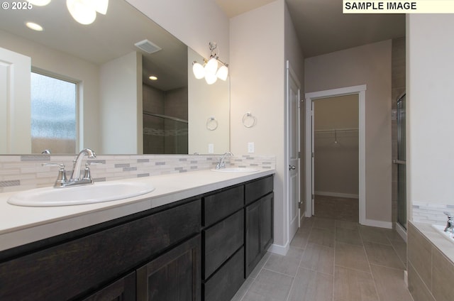 bathroom with plus walk in shower, tile patterned floors, backsplash, and vanity