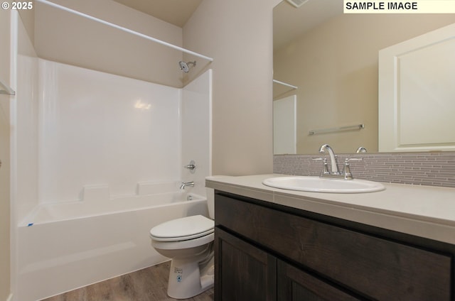 full bathroom featuring toilet, wood-type flooring, backsplash, shower / bathtub combination, and vanity